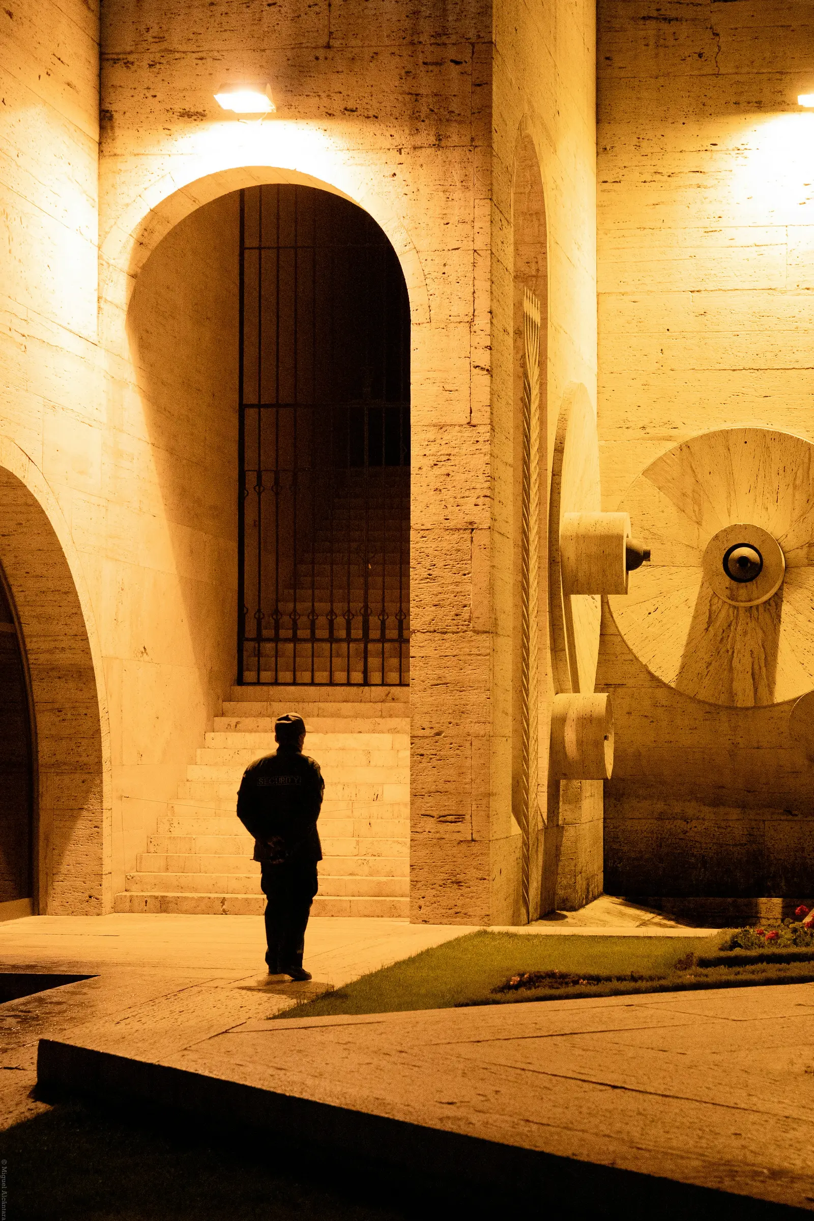 Guardia de pie bajo los arcos iluminados de un edificio durante la noche